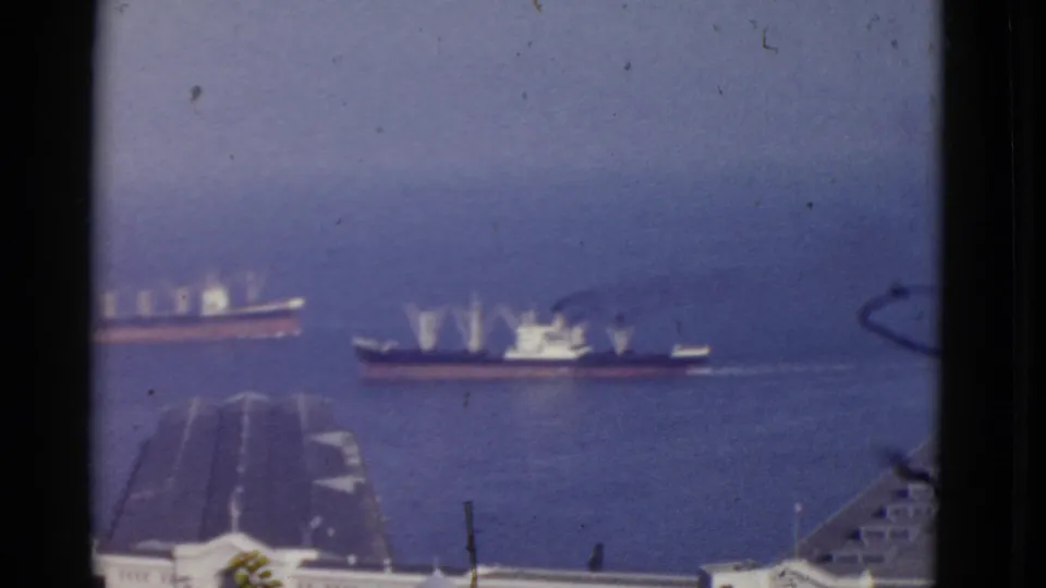 1952 San Francisco Bay home-movie frame showing two ships on blue water, seen from an elevated view with rooftops below.