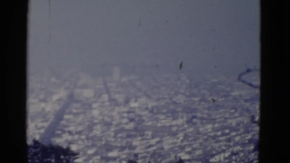 Final 8mm frame of a hazy San Francisco city panorama, with dark foreground trees and soft blue-gray exposure.