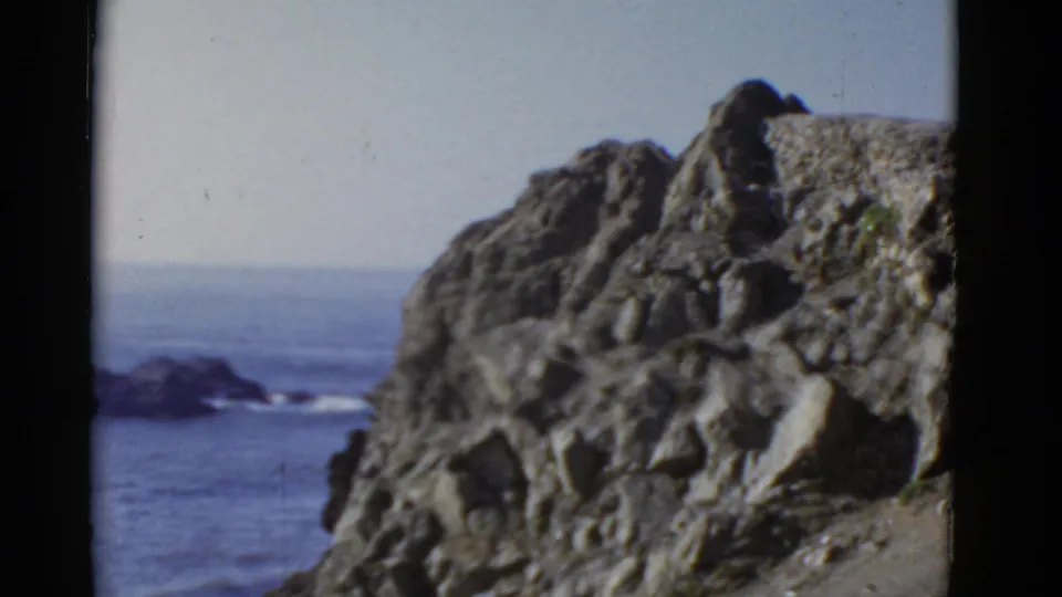 The final frame holds on San Francisco coastal rocks above the ocean, with no central person visible and a soft 8mm home-movie look.