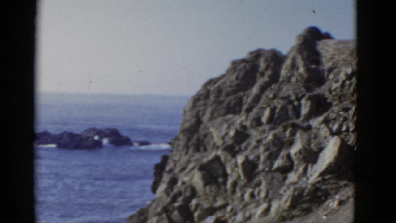 1952 8mm view near San Francisco showing a rugged cliff edge, blue ocean, distant rocks, and pale horizon.