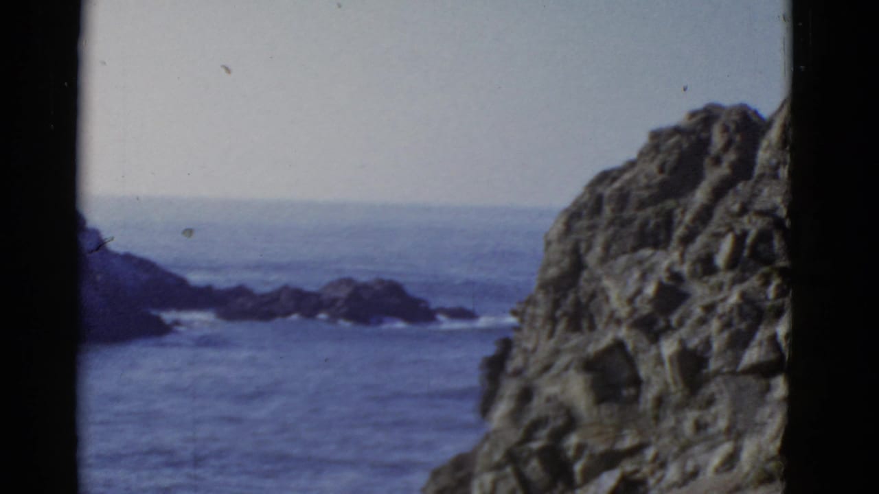 Ocean horizon and offshore rocks seen beside a large foreground cliff.