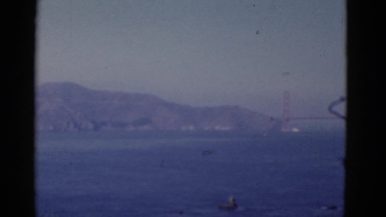 Golden Gate Bridge tower and hills seen through haze across the bay.