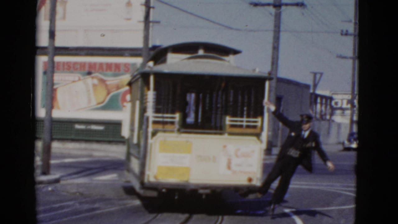 In 1952 San Francisco, a uniformed conductor appears to step off the back of a cable car beside street rails and a beer billboard.