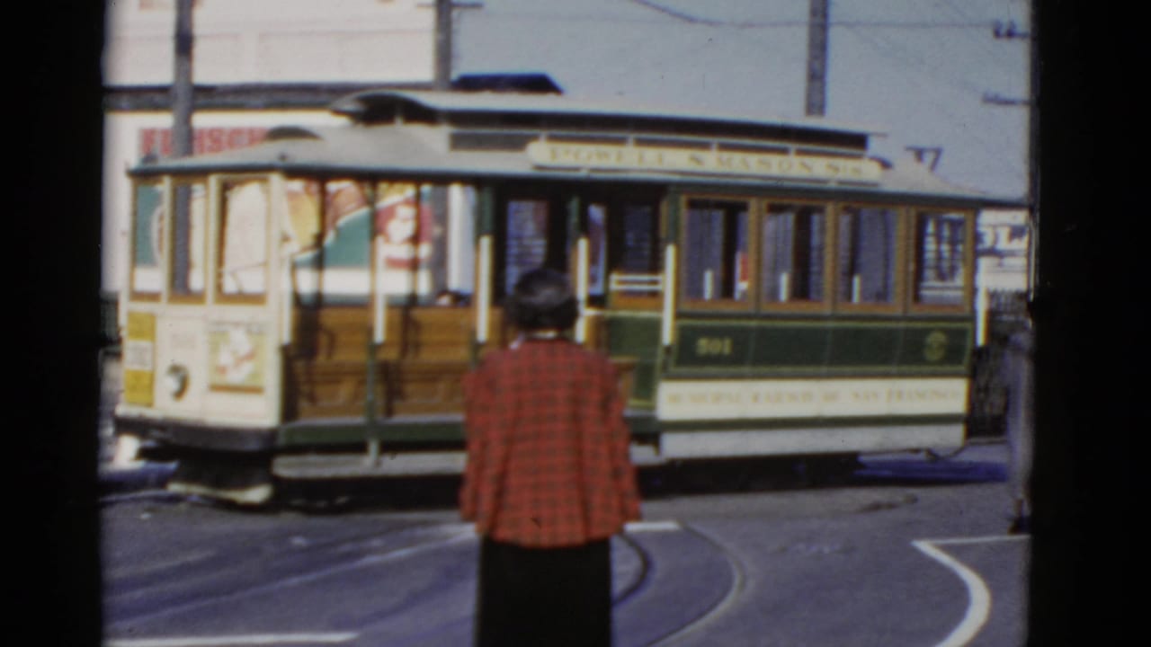 1952 San Francisco street view with cable car 501 passing as a woman in a red plaid jacket watches from the foreground.