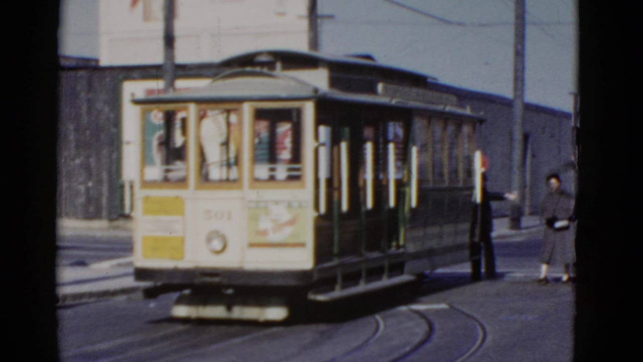 1952 San Francisco street scene with cable car 501 approaching or stopped on tracks as pedestrians wait nearby.