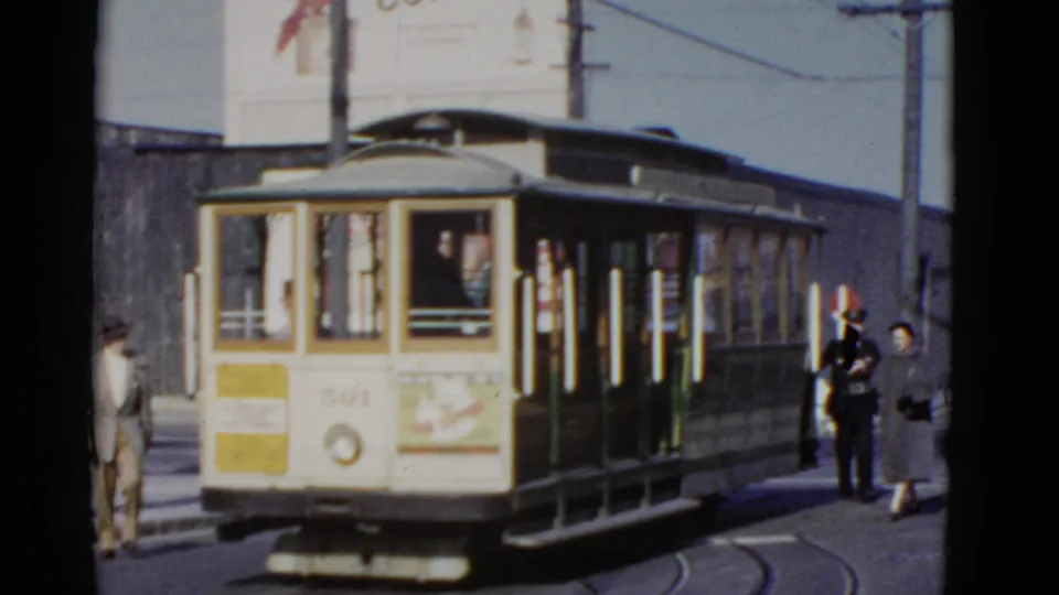 Cable car 501 in San Francisco with passengers or pedestrians gathered at the side during a brief street stop.