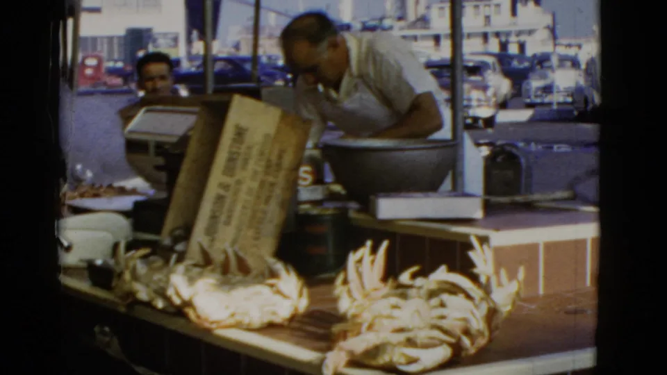 San Francisco seafood stall with vendors working behind a counter covered with crabs and other seafood in 1952 footage.