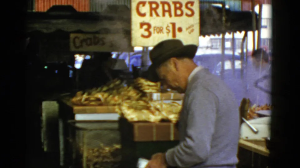 A suited man in a fedora appears to handle payment or belongings at a 1952 San Francisco crab stand.