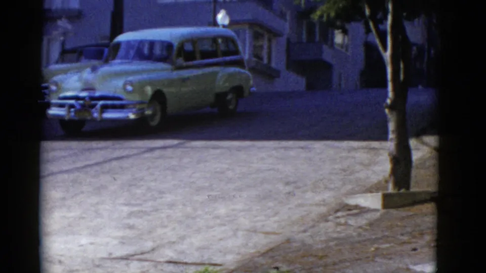 1952 San Francisco street view with a rounded light-colored station wagon and building facades in the background.