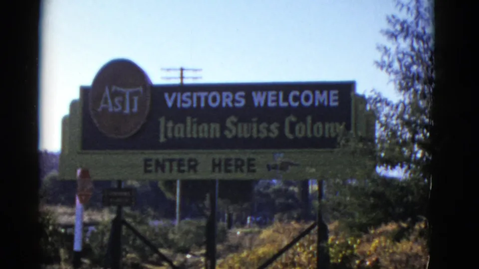 1952 8mm frame holding on the Italian Swiss Colony roadside sign at a visitor entrance in California.