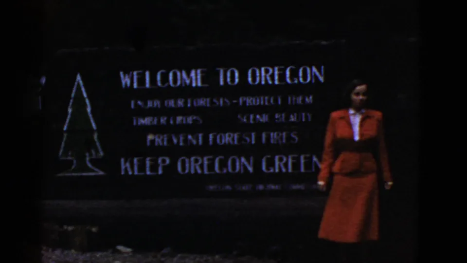 The Oregon welcome and Keep Oregon Green sign appears darker, with the woman in red standing at the right edge.