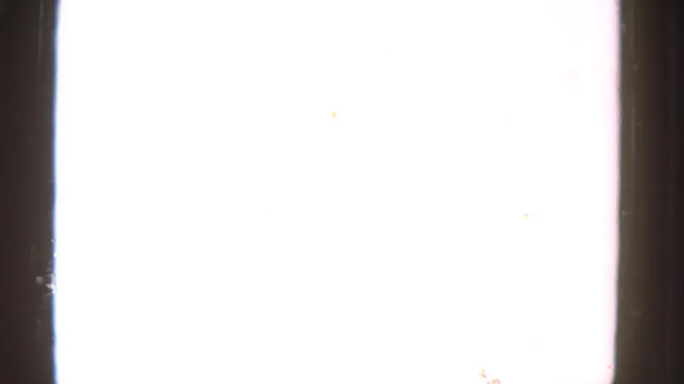 An overexposed 8mm frame appears mostly white, with faint dust marks and dark film edge visible at the side.