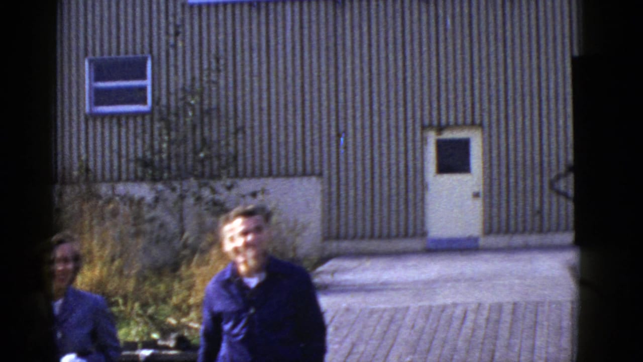 Man and partially obscured woman near a building as the camera follows them.