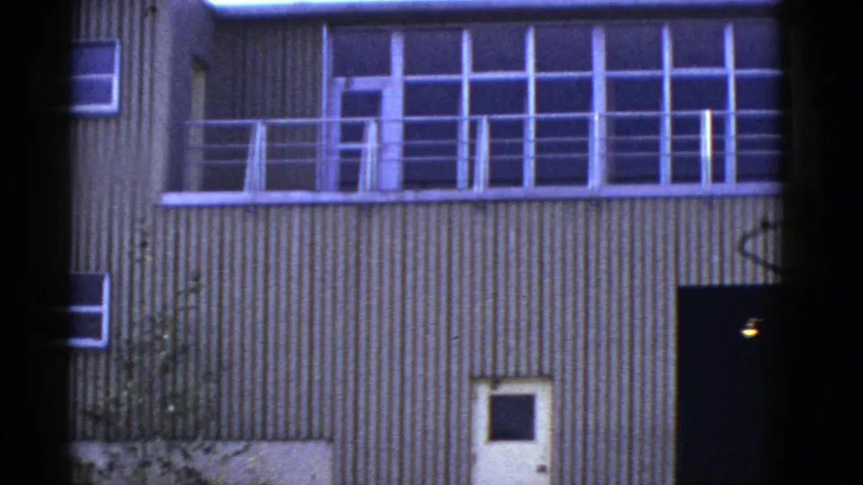 Early 1950s San Francisco frame showing the building facade, balcony railing, windows, and white door after the people leave frame.