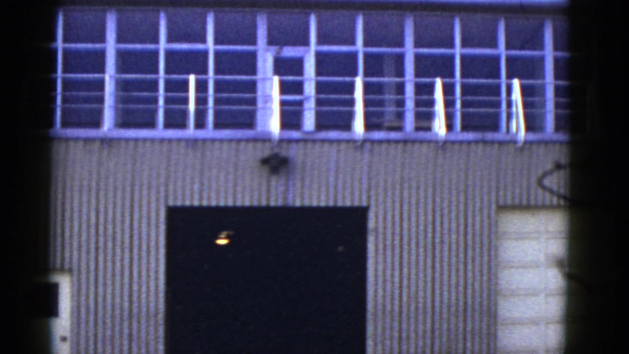 1950s San Francisco warehouse exterior with corrugated siding, upper grid windows, a railing, and a dark service opening.