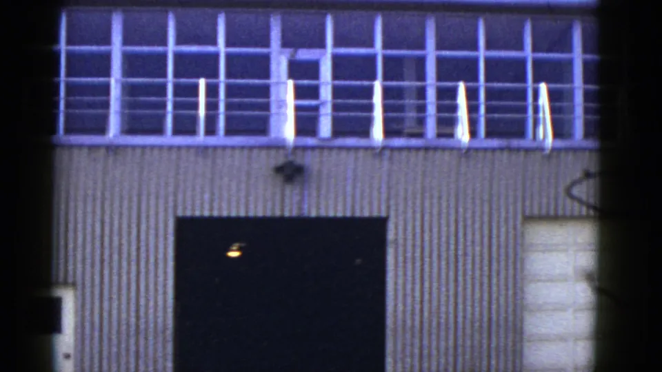 1950s San Francisco warehouse exterior with corrugated siding, upper grid windows, a railing, and a dark service opening.