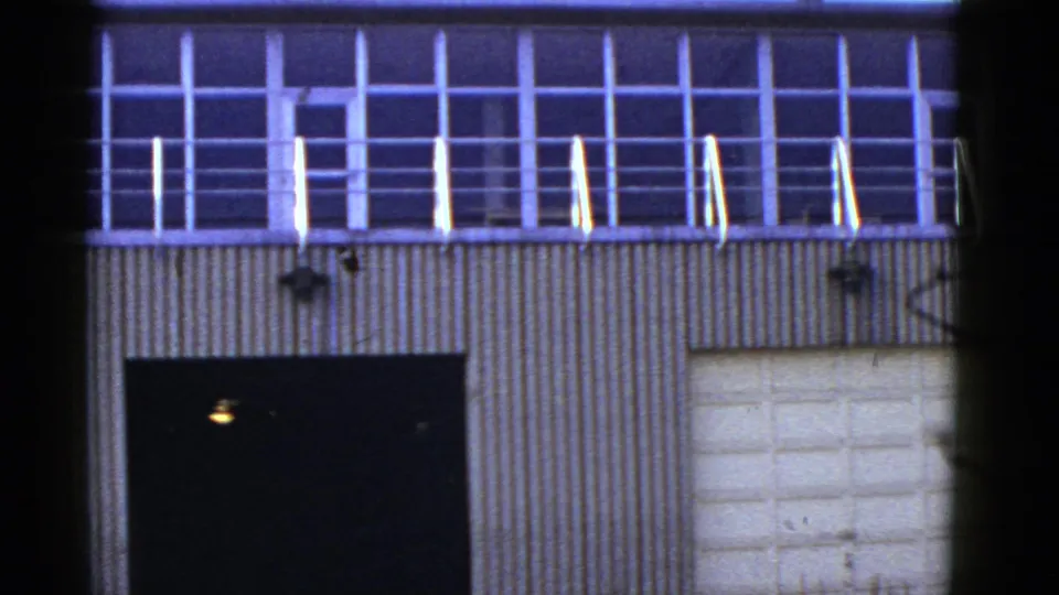1950s San Francisco industrial building exterior showing upper grid windows, railing, corrugated wall panels, and large doors.