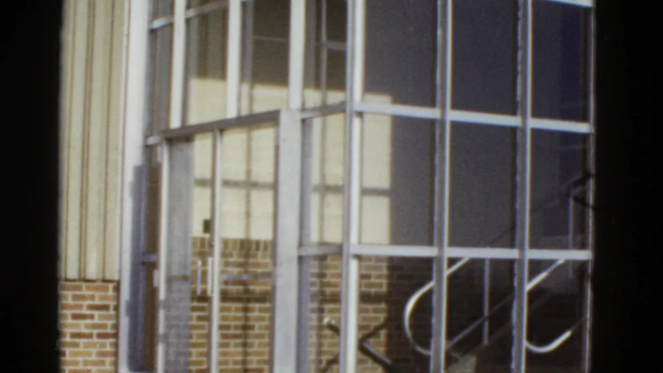 1950s San Francisco building exterior showing a large metal-framed glass entry with an interior stairway visible beyond it.