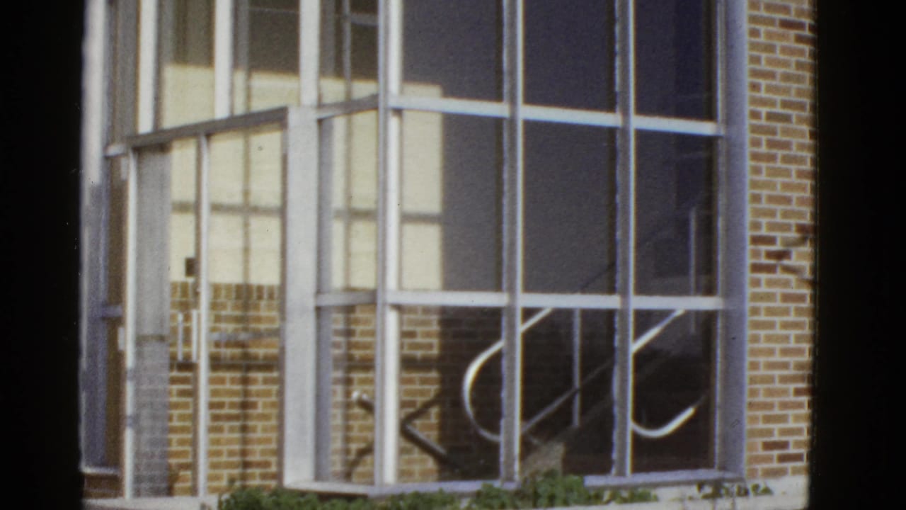 Window grid with brick wall, pale panels, and curved stair rail reflections.