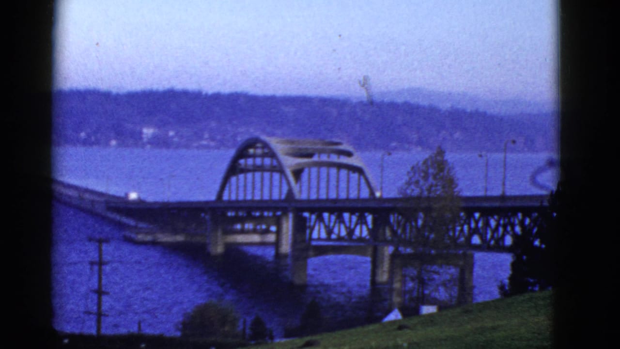 Bridge span over water with distant shoreline and dark film borders.