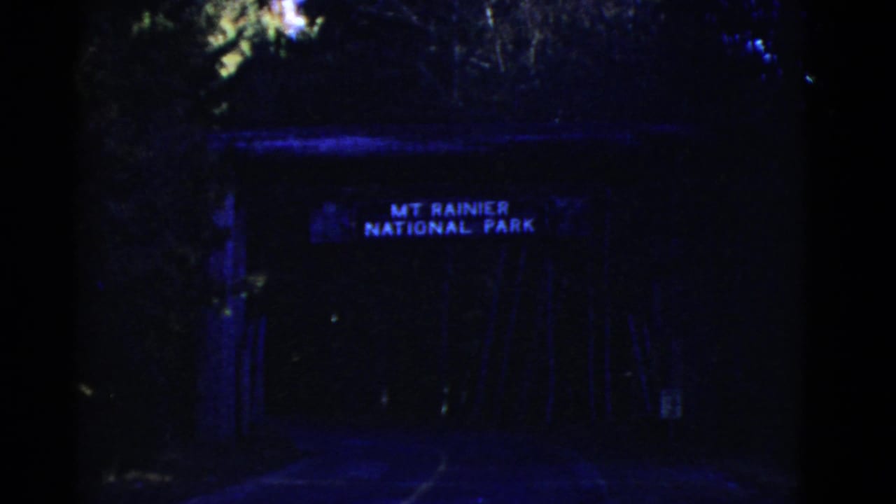 Dark gateway or tunnel entrance with a sign reading MT RAINIER NATIONAL PARK.