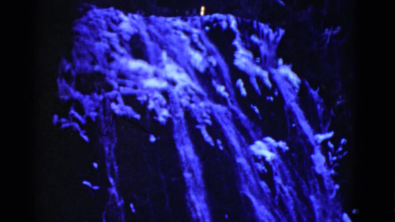 1952 San Francisco home-movie frame with bright blue water streams descending over a dark rocky surface.