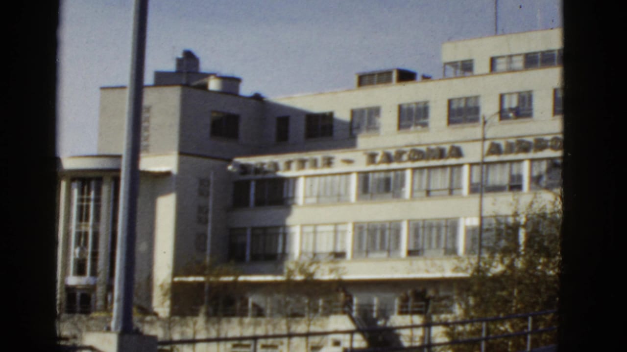 1950s 8mm frame of a modernist airport building with Seattle Tacoma Airport signage, viewed through dark vertical framing.