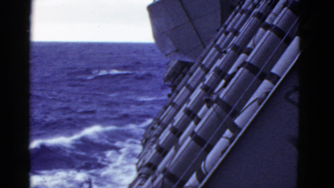 1952 8mm shipboard view near San Francisco metadata context, looking past secured cylindrical gear toward rough blue water.