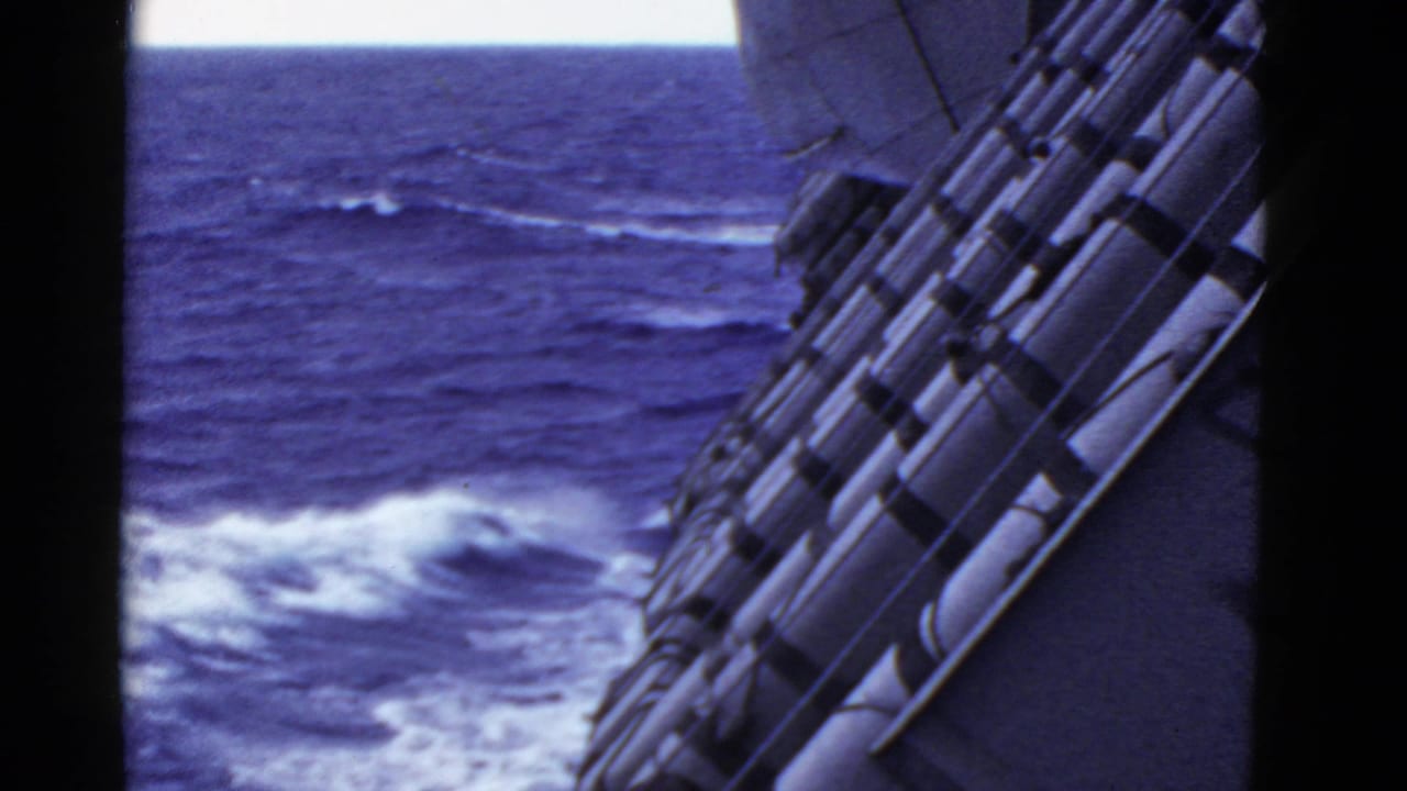 Angled ship side and row of cylindrical gear beside open ocean.