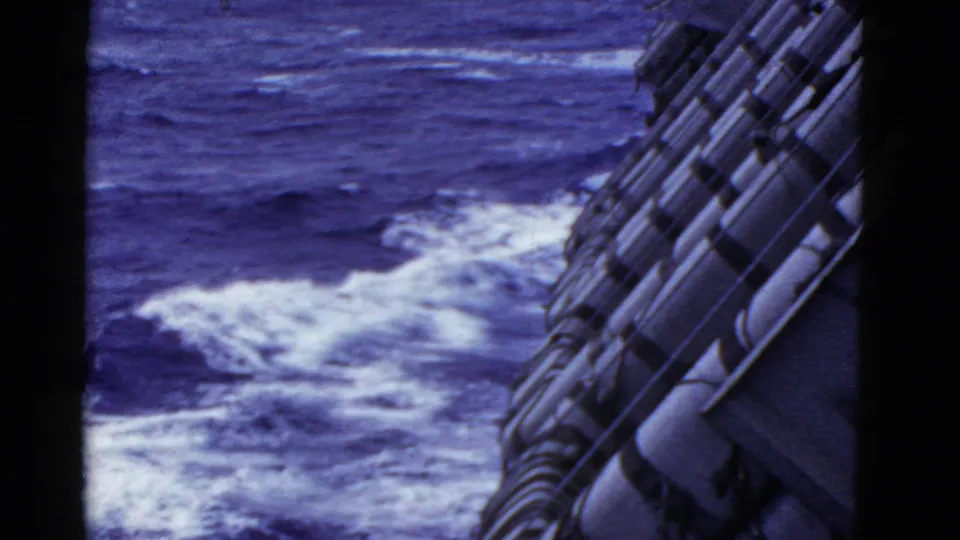 End frame of the 1952 shipboard ocean view, showing vessel fittings and churned water alongside the ship.