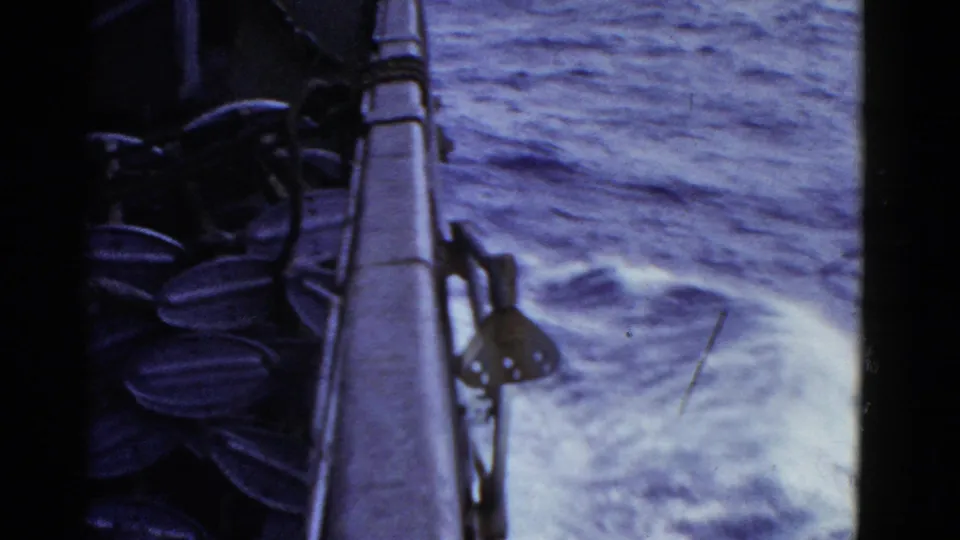 Final frame shows the naval vessel's side railing and hardware beside foaming wake, with blue-purple 8mm color shift.