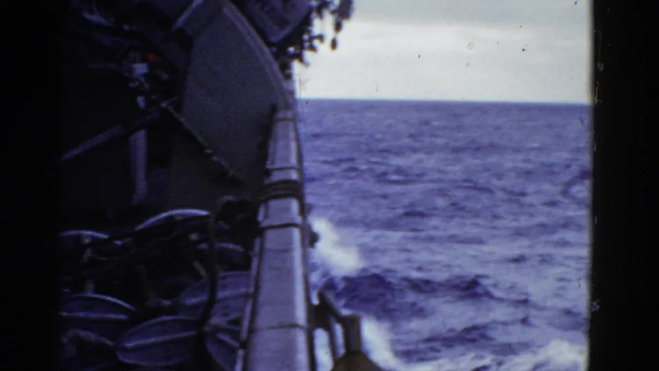 A 1952 8mm shipboard view from the San Francisco reel, looking past the rail toward blue water and wake.