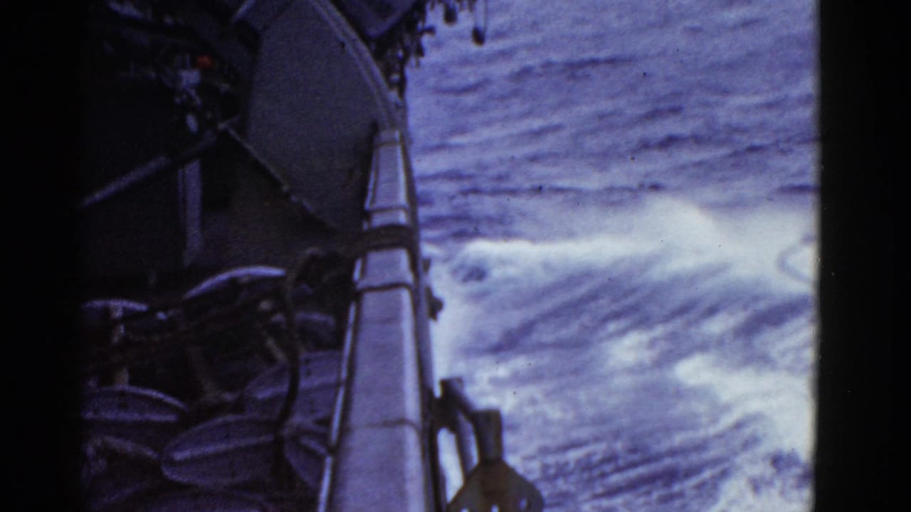 Ship deck edge with white wake spreading across open water.