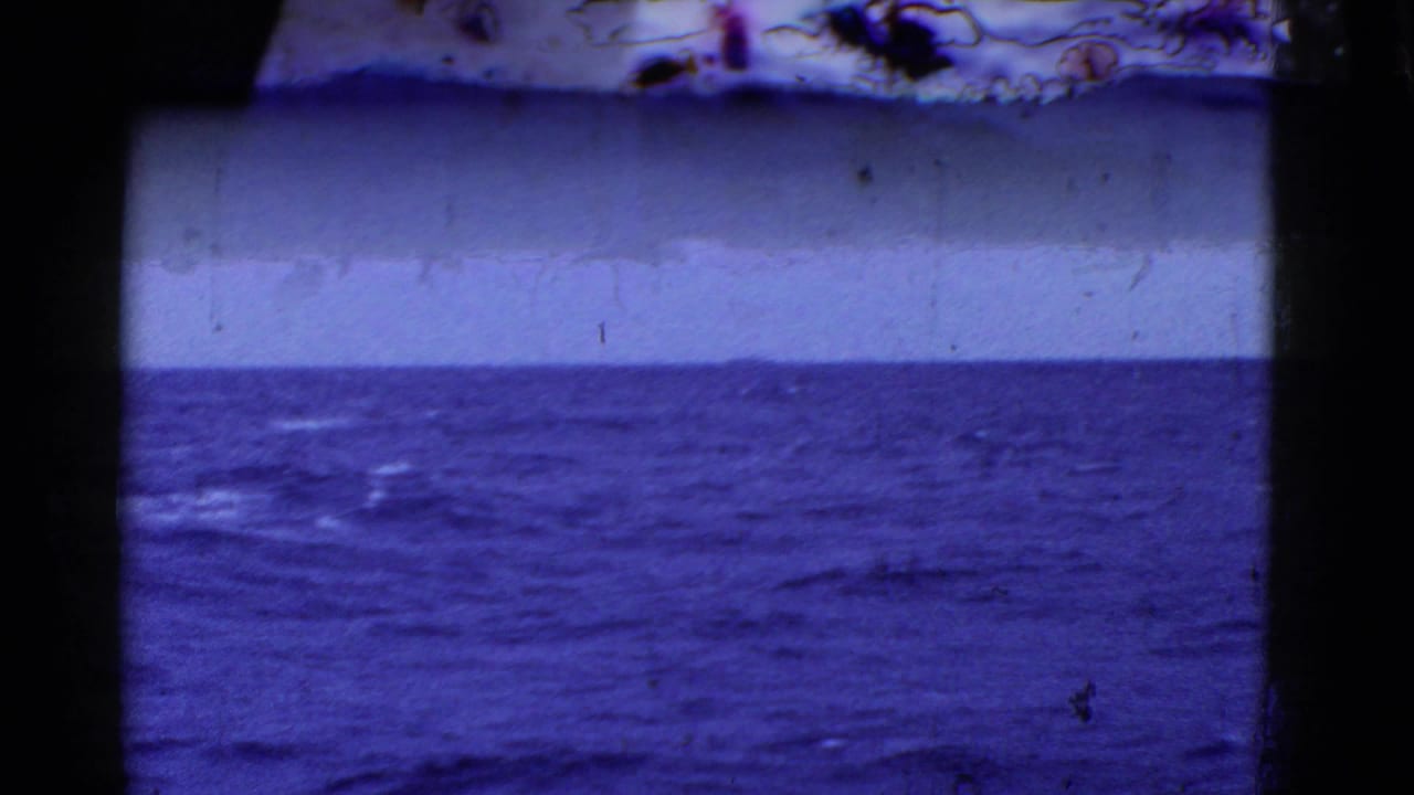 Metadata-supported 1950s San Francisco-area home-movie frame showing open blue ocean beneath an overcast sky, with dark window or railing edges and visible film wear.