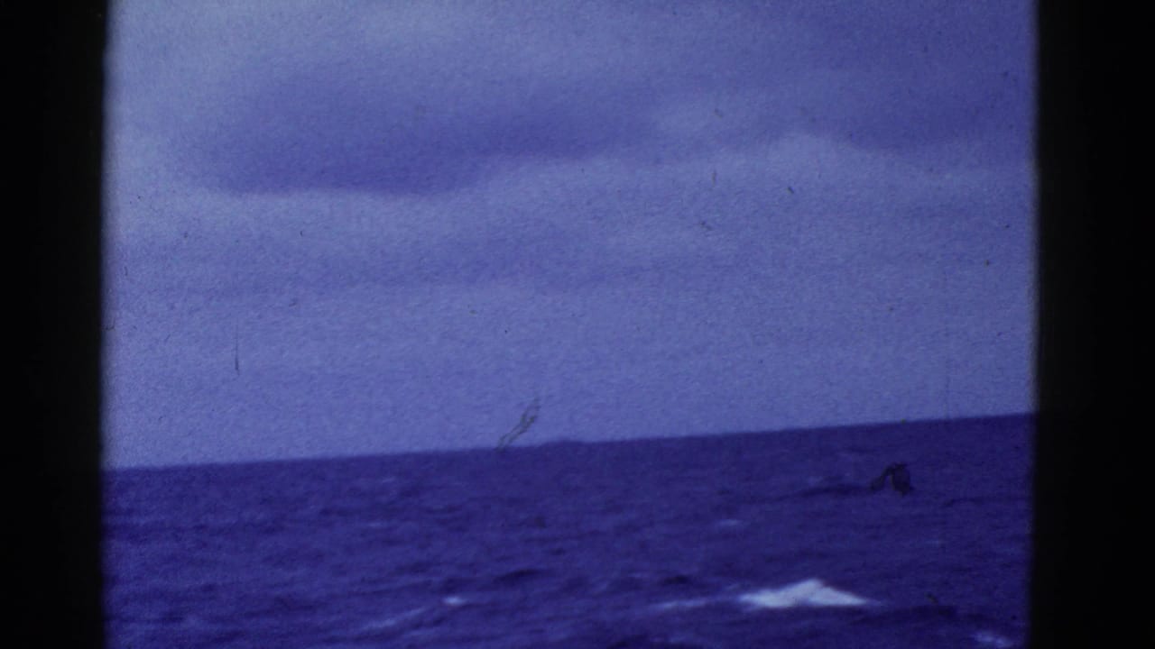 1952 8mm shipboard view near San Francisco with open sea, low clouds, distant horizon, and a small white wake on the surface.