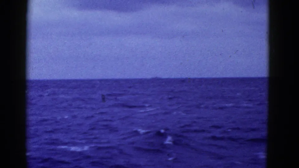 1952 8mm maritime frame near San Francisco showing choppy blue water, white wake streaks, a low horizon, and cloudy sky.