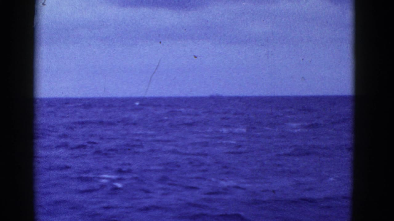 Blue ocean horizon with pale sky and visible dust marks on the film.