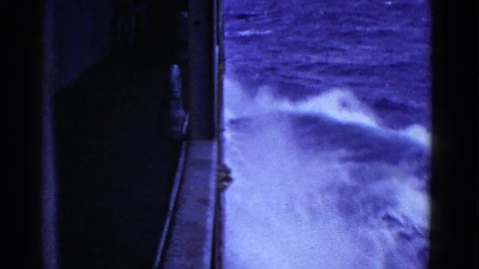 A broad wash of white wake spreads next to the ship side in blue-tinted 1952 San Francisco maritime footage.