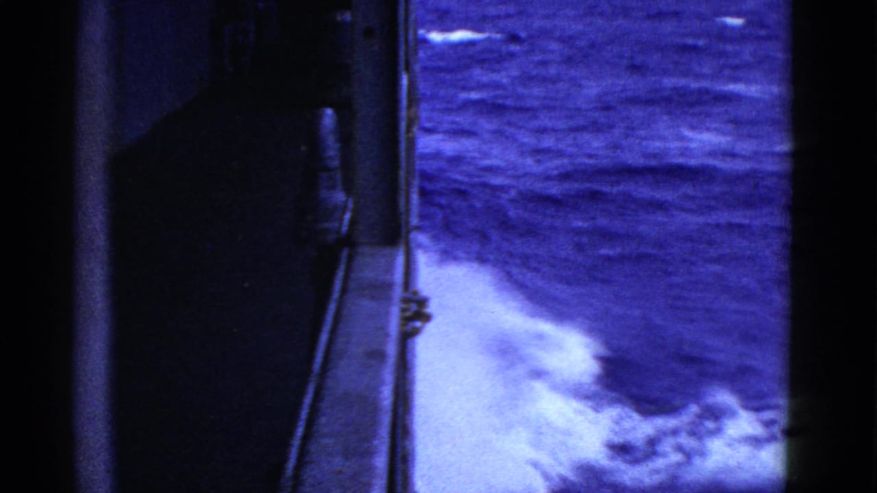 Foaming ocean wake seen beside a dark ship structure.