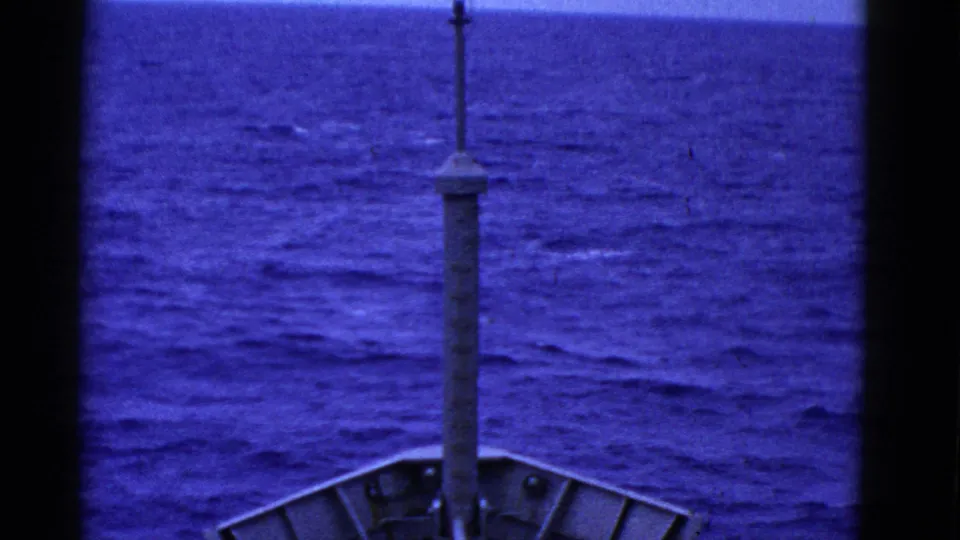 Blue-tinted 8mm frame of a ship bow and mast with rolling ocean ahead, consistent with the clip's San Francisco maritime metadata.
