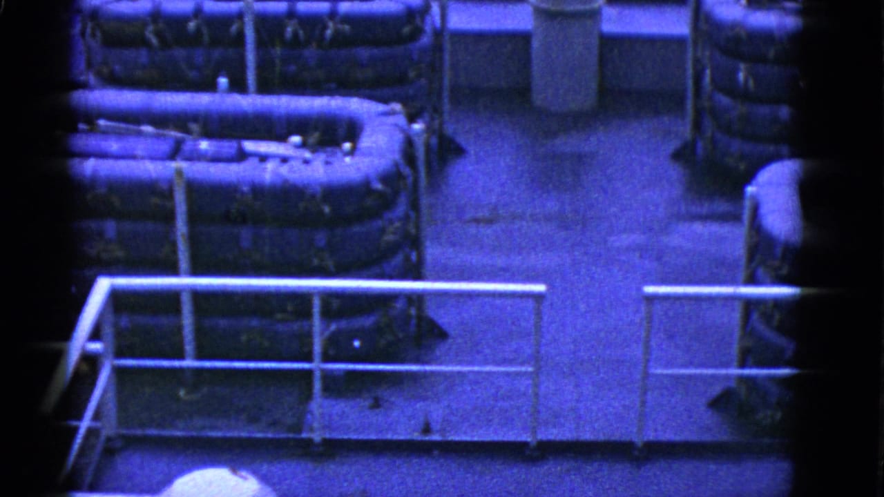 1952 San Francisco home-movie frame showing an industrial-looking military rest area with railings above and seated soldiers partly visible below.
