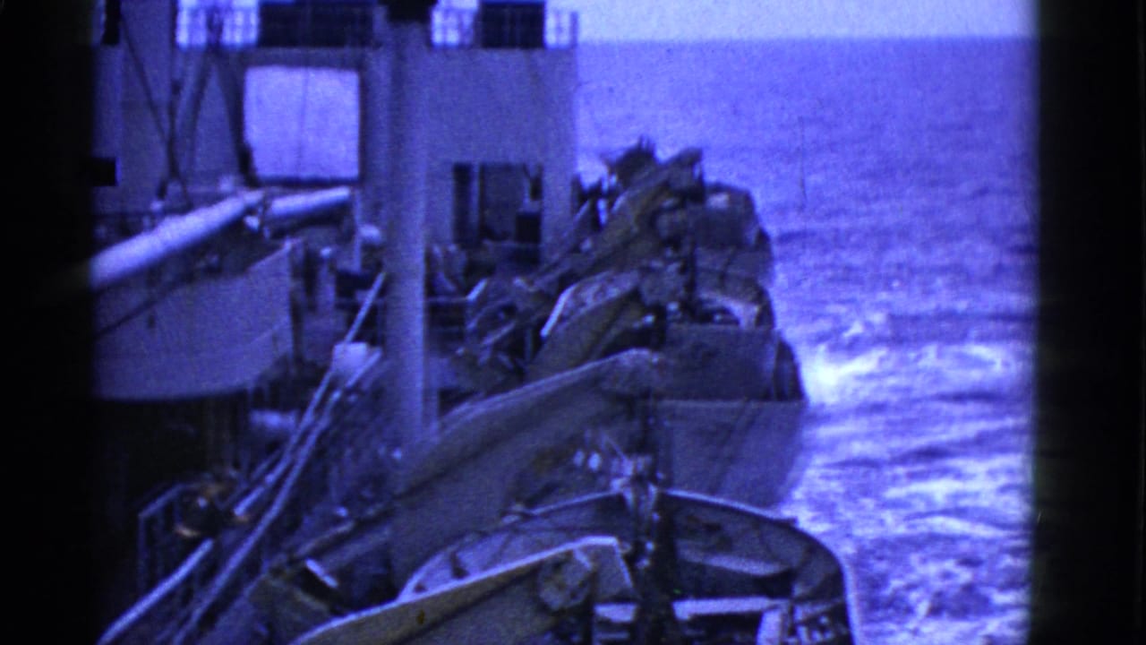 A row of lifeboats and davits lines the ship above churning water.