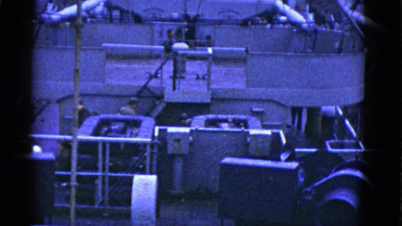 Blue-tinted 8mm frame of men on a San Francisco vessel deck near machinery, railings, pipes, and structural fittings.
