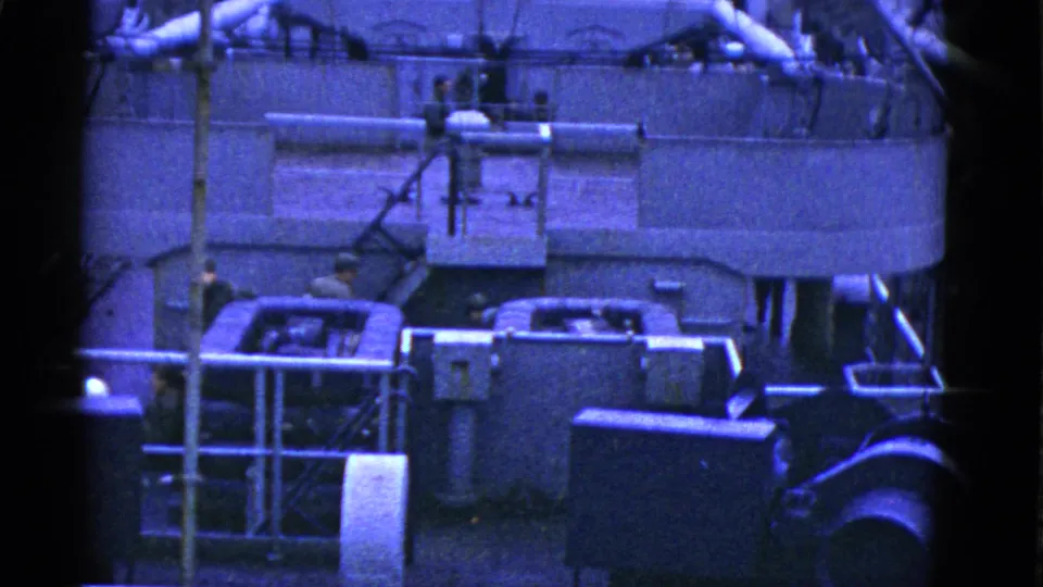 Blue-tinted 8mm frame of men on a San Francisco vessel deck near machinery, railings, pipes, and structural fittings.