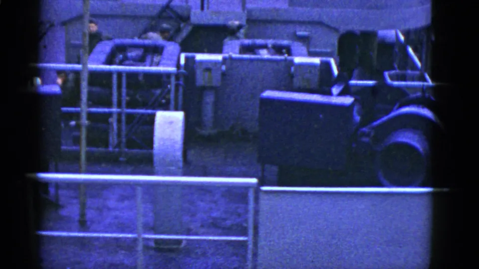 1950s San Francisco ship deck view with machinery, railings, pipes, and partially visible crew members captured on blue-tinted 8mm film.