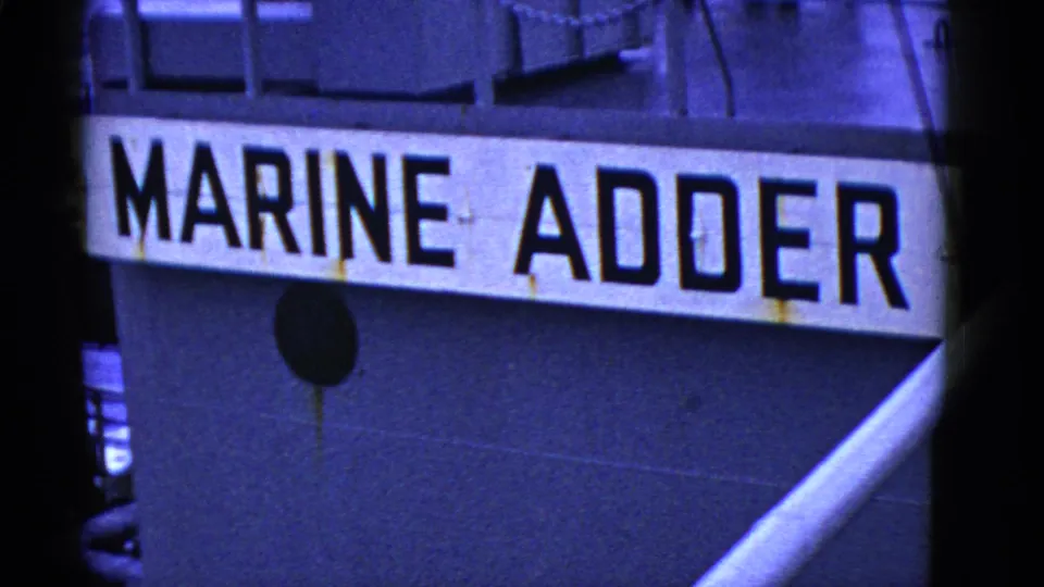 Close 8mm frame of the Marine Adder name painted across the side of a vessel in San Francisco maritime footage.
