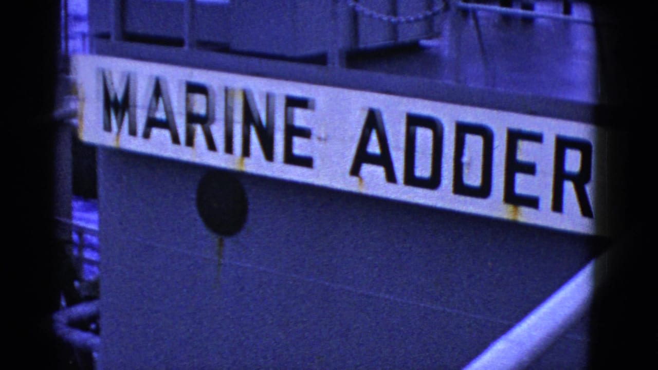 1950s 8mm close-up of the MARINE ADDER name painted on a ship hull, with dark metal plating and rust marks visible.