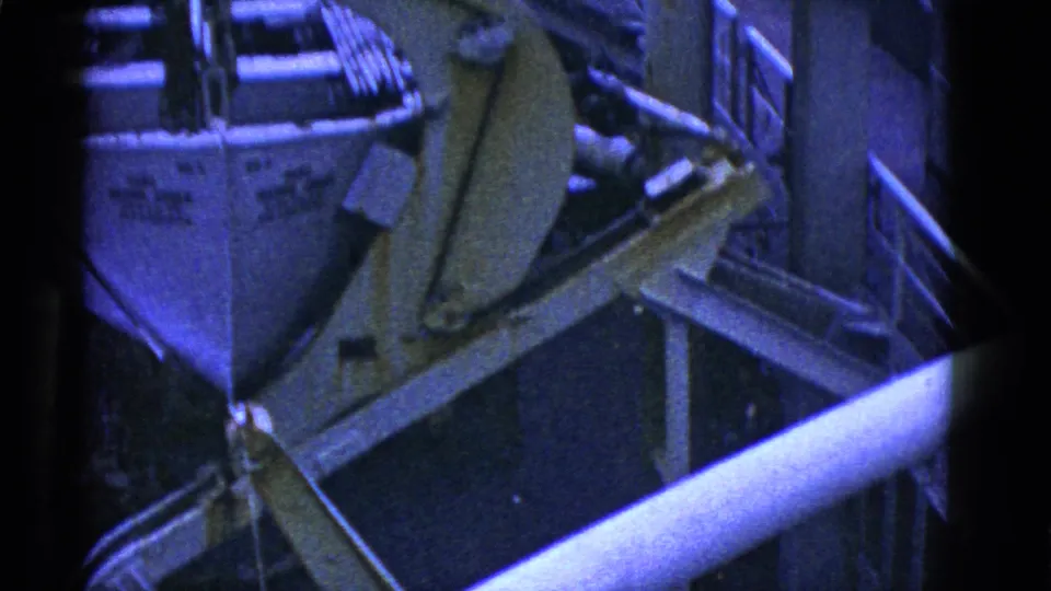Early 1950s San Francisco 8mm frame showing the bow of a small boat beside a crane arm, railings, and deck equipment.