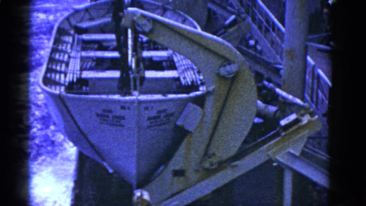 1952 San Francisco-area 8mm frame showing a white lifeboat secured on davits with water visible beside the vessel.