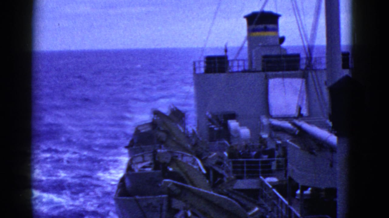 Vessel structure and deck equipment frame the ocean horizon and wake.